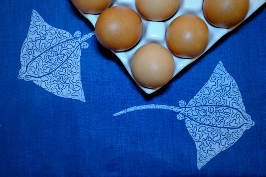 &BEYOND Eagle Ray Blues napkin displayed beside a dish of food.