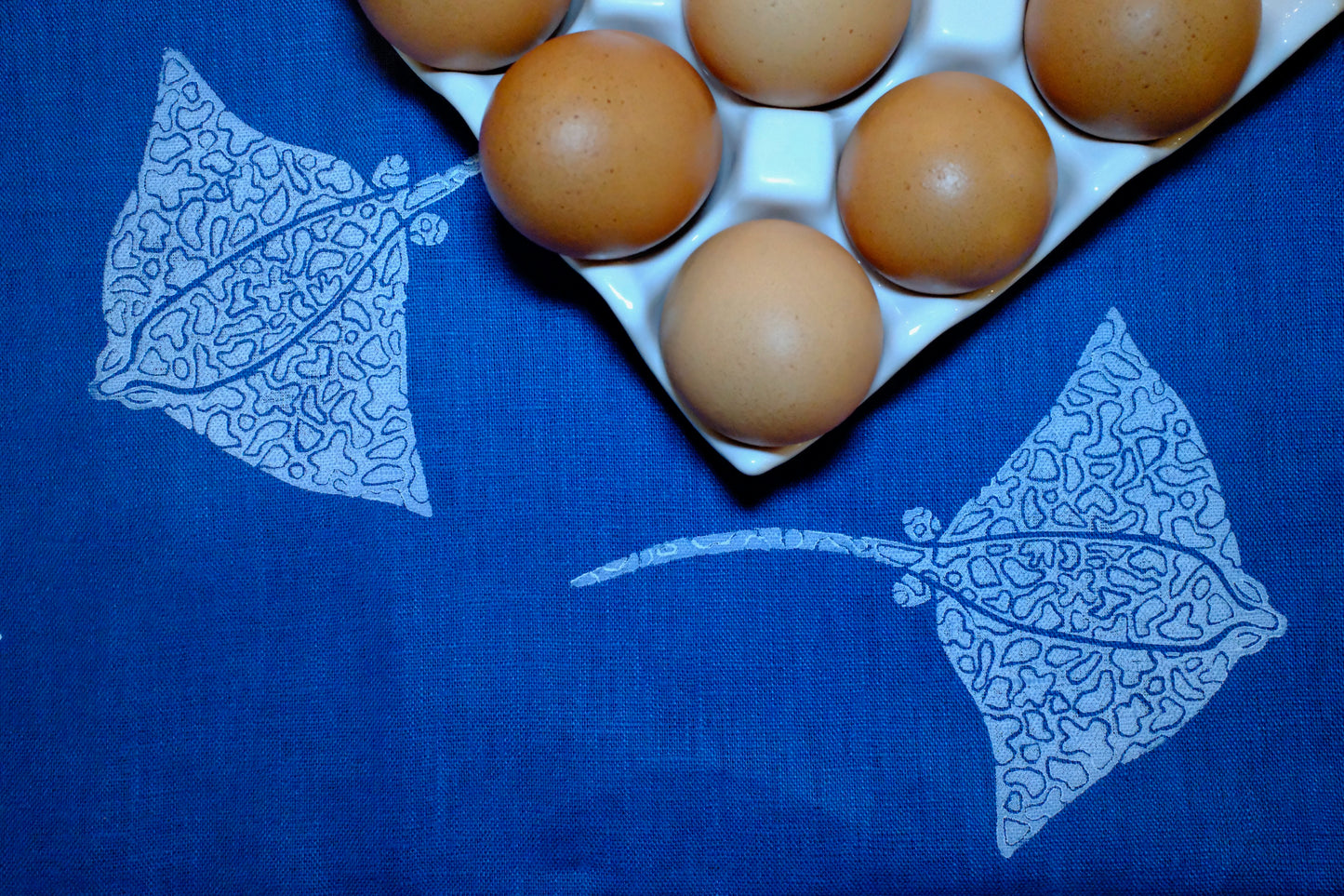 &BEYOND Eagle Ray Blues napkin displayed beside a dish of food.
