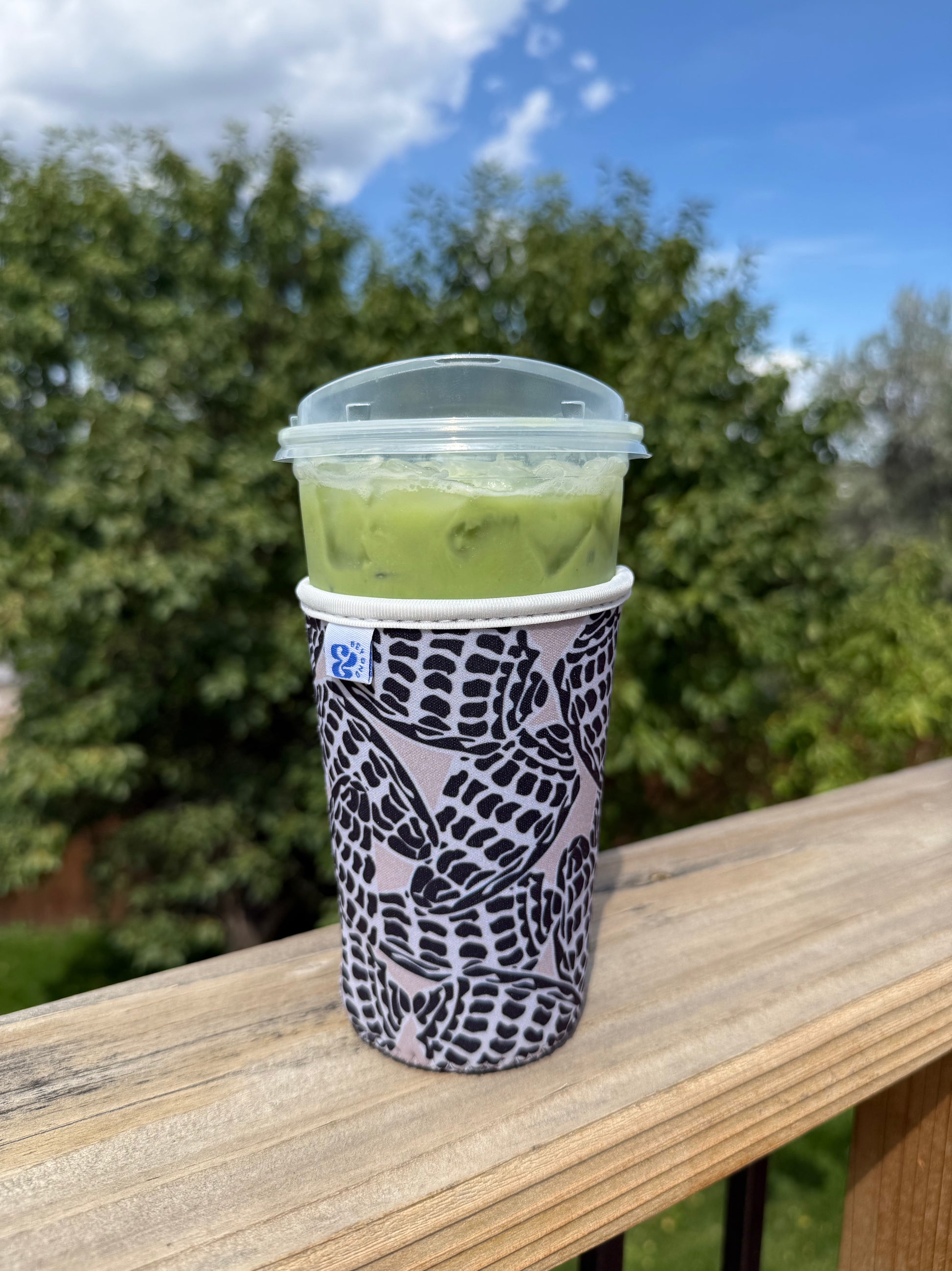 Lifestyle photo of the &BEYOND Hebrew Shell coozie outside.