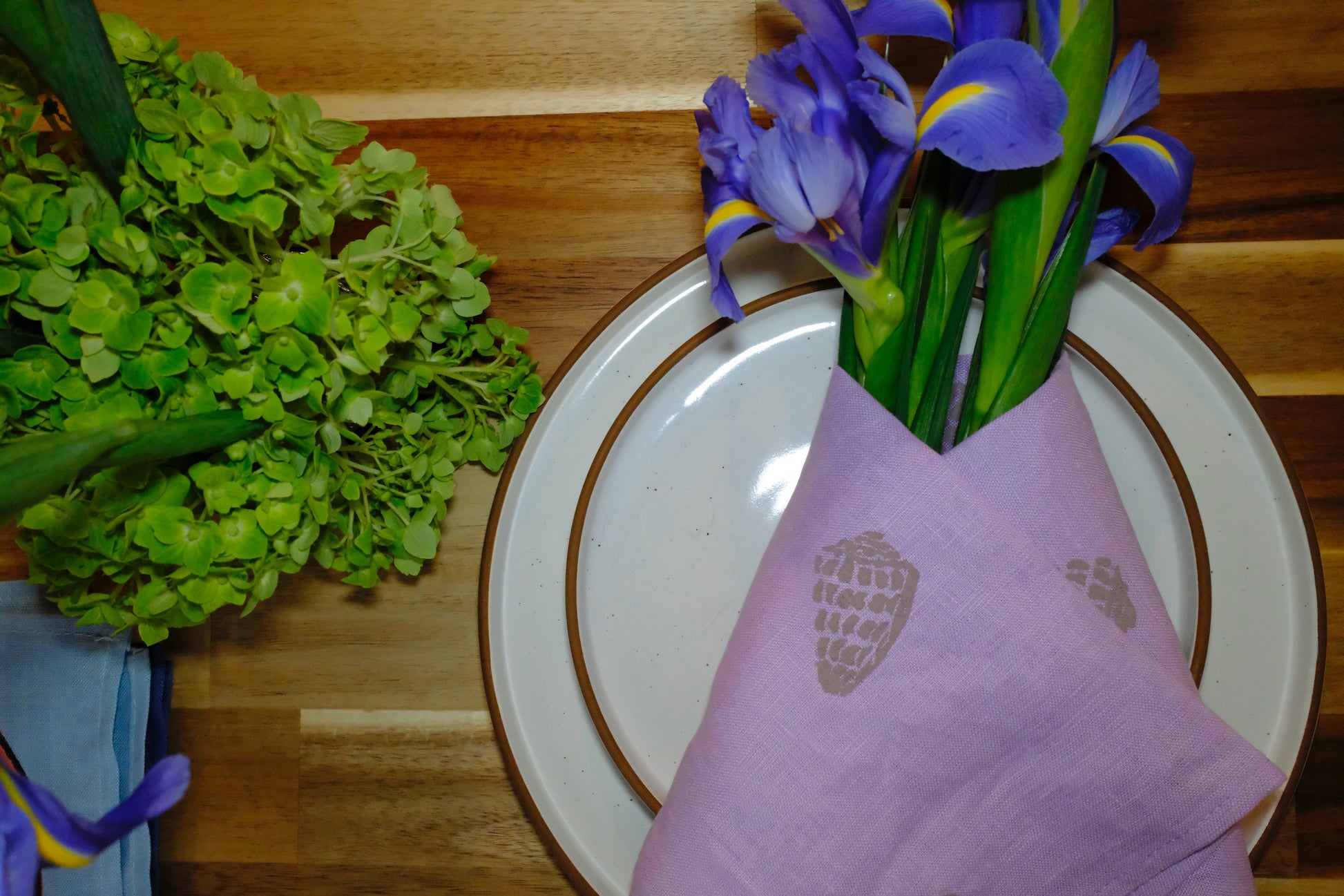 Flatlay of &BEYOND Hebrew Shell linen napkins on a wood tabletop.