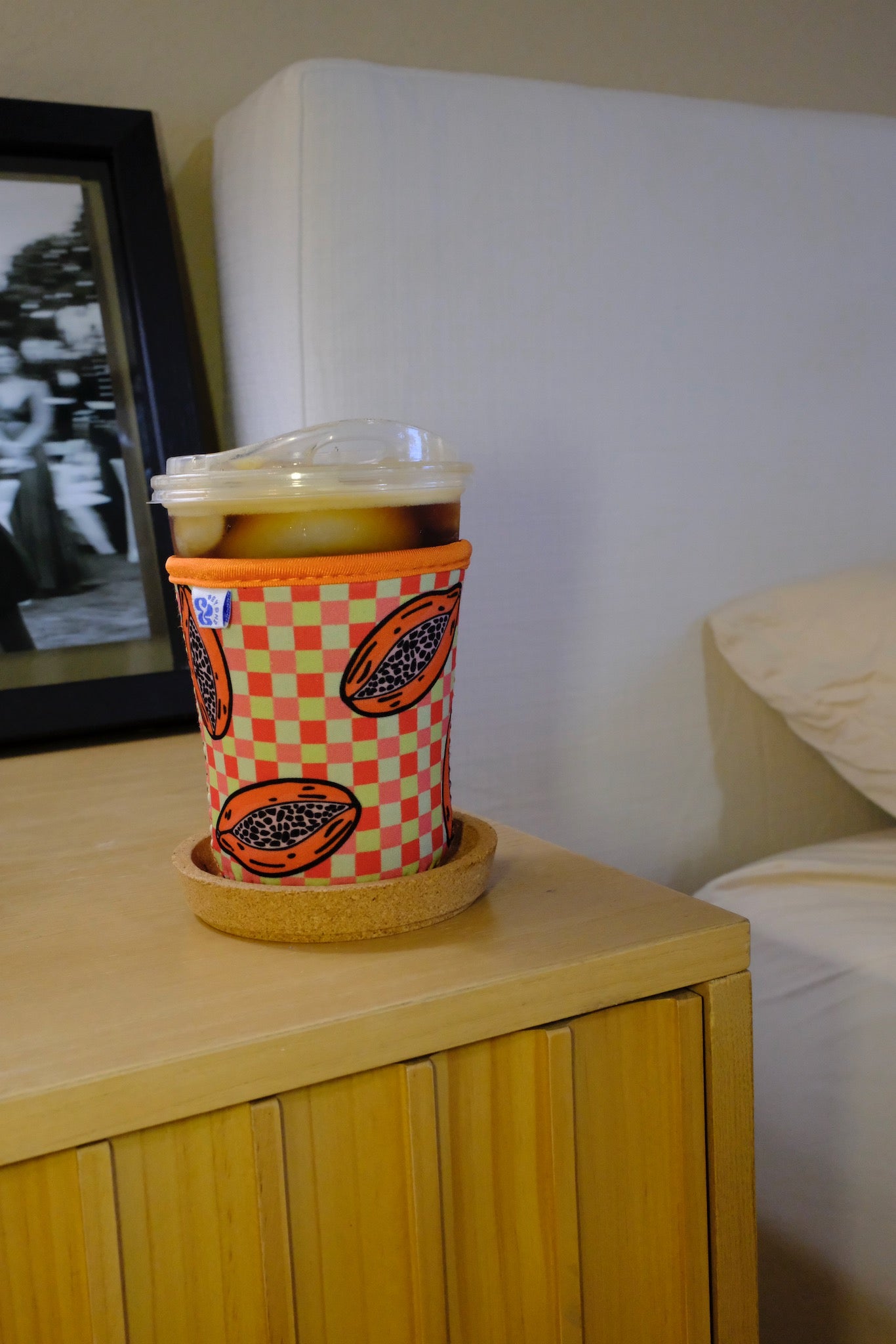Lifestyle photo of the &BEYOND Papaya Dream coozie on a warm wooden table.
