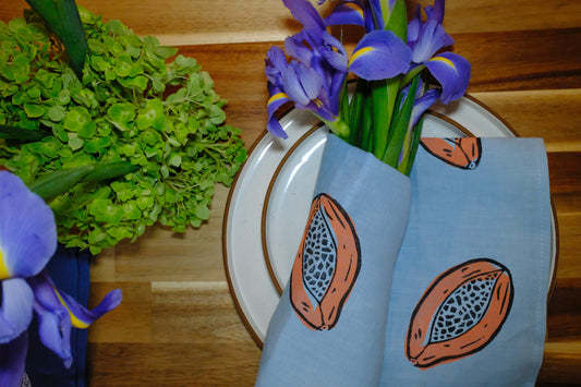 Lifestyle table display featuring &BEYOND Papaya Dream linen napkins in a warm dining scene.