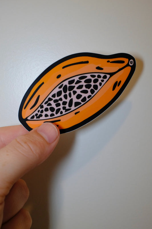 Hand holding an &BEYOND Papaya sticker with bold tropical colors.